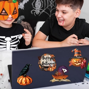 Close-up of Halloween stickers including pumpkin and wizard hat on a laptop cover