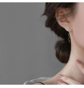 Dettaglio di orecchini a stella in argento con nappe ondulate e zirconi su una modella