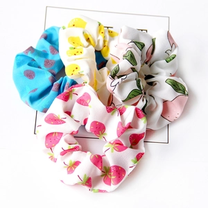 Close-up of four fabric hair scrunchies with strawberry, lemon, and peach fruit patterns