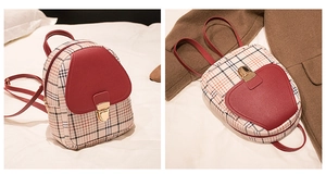 Detail view of the elegant red leather flap and metallic heart clasp on a plaid mini backpack