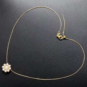 Detail of elegant gold necklace featuring a pearl flower pendant in a heart-shaped layout