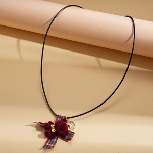 Close-up of winter necklace with red plaid bow and fuzzy bear pendant on a display stand