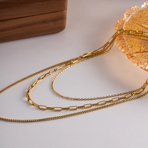 Detail of 18K gold layered necklace featuring paperclip and box chain textures