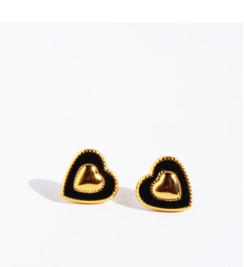 Macro shot of gold heart stud earrings with black enamel fill and a central gold heart