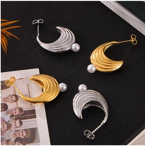 Dettaglio orecchini a forma di U con texture a onde in oro e argento e perle bianche