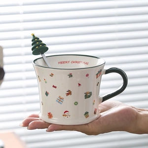 Handheld view of a festive Christmas ceramic mug with Santa patterns and green handle