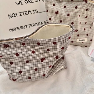 Dettaglio della trousse grigia a pois con motivo a fiocco e cerniera metallica lucida