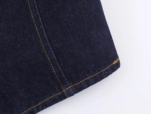 Vue détaillée des coutures contrastées jaunes sur le tissu en denim bleu foncé