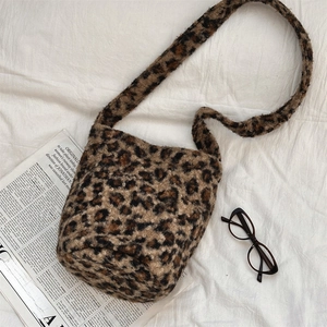 Detail of leopard print plush bucket bag on white fabric with glasses and newspaper
