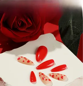 Detail view of red heart pattern and glossy almond nails on stone with red rose