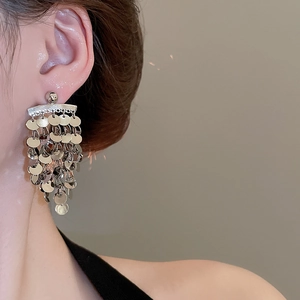 Detailed view of silver long fringe earrings with layered sequins on female model