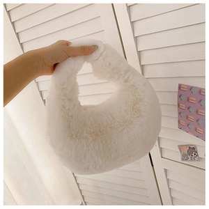 Close-up of white fuzzy plush dumpling handbag featuring soft faux fur and curved handle