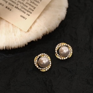 Detailed macro view of golden spiral earrings with grey pearls and shiny rhinestones