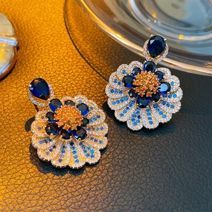 Detail shot of vintage floral earrings with blue and orange crystals in gold finish