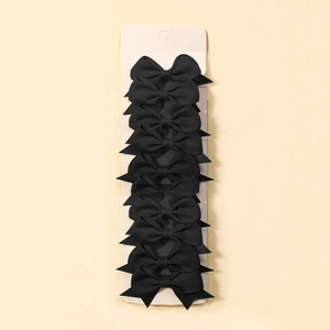 Close-up of black grosgrain ribbon bow hair clips on a beige display card