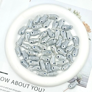Macro detail of gray ceramic fish beads for DIY jewelry making on white tray
