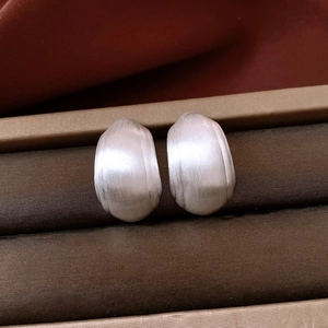 Vue macro de boucles d'oreilles ovales épaisses en métal brossé argenté poli