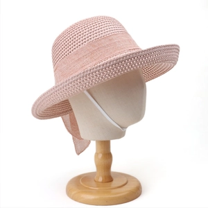 Pink woven straw sun hat detail featuring a large bow and white elastic chin strap