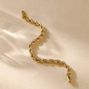 Macro view of 14K gold-plated twisted rope chain bracelet with metallic woven texture