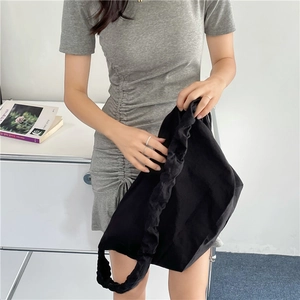 Dettaglio della borsa a tracolla in nylon nero con tracolla arricciata e design minimal
