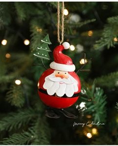 Detailed view of hand-painted Santa metal ornament hanging on a festive Christmas tree branch