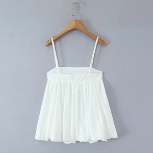 Detailed view of white spaghetti strap camisole with tiered babydoll hem on hanger