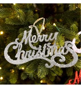 Macro shot of silver Merry Christmas ornament with glitter finish on a festive tree