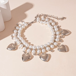 Detail of double-layer necklace with white faux pearls and silver heart pendants