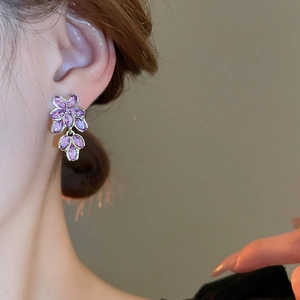 Detailed close-up of violet floral earrings with crystals on gold plated alloy setting