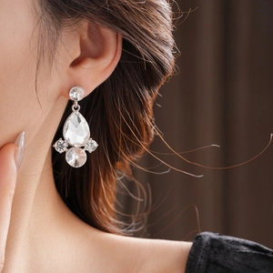 Dettaglio di orecchini a goccia in argento con cristalli indossati su modella