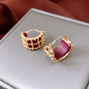 Detail of 18K gold-plated openwork hoops with burgundy leather inlay on velvet box