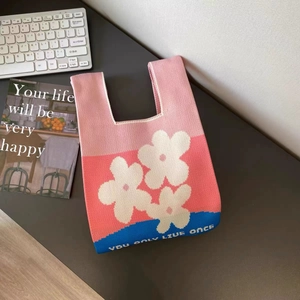 Dettaglio della borsa in maglia tricolore con motivi floreali e base blu a contrasto