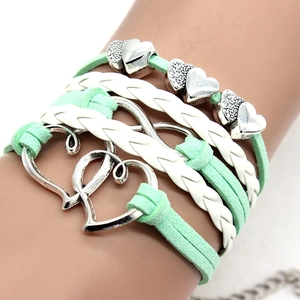 Detail of multi-layer white and mint green woven leather bracelet with silver heart charms
