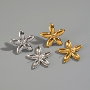 Détail de quatre boucles d'oreilles fleurs en or et argent sur fond gris