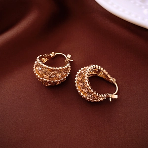 Elegant gold oval hoop earrings with champagne crystal pavé on dark satin background