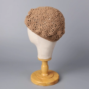 Nahaufnahme der hohlen Häkeltextur einer handgefertigten braunen Strickbaskenmütze