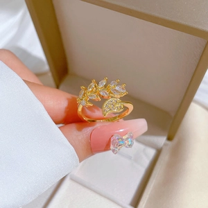 Elegant gold leaf open ring with zircon stones held against a jewelry box background