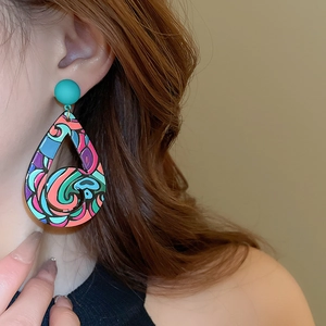 Detail of artistic colorful graffiti teardrop earrings on model with abstract painted patterns