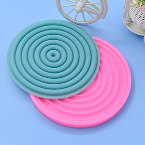 Pink and grey round silicone heat-resistant mats with concentric non-slip ripple design
