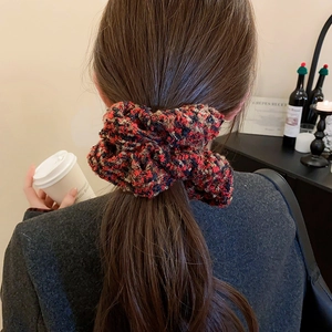 Détail d'un chouchou en tweed à carreaux sur queue de cheval dans un cadre de café