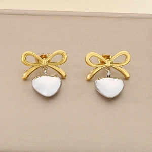 Détail de boucles d'oreilles cœur bicolores dorées et argentées sur un support mat