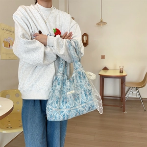 Close-up of blue paisley tote bag featuring delicate white lace trim and bow ribbon detail