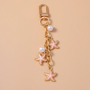 Detailed close-up of golden keychain with pink starfish charms and white faux pearls