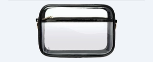 Detail view of transparent PVC travel bag with black trim and gold metal zipper hardware