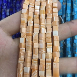 Gros plan de perles cubiques en pierre naturelle rayées orange et blanc pour bijoux DIY