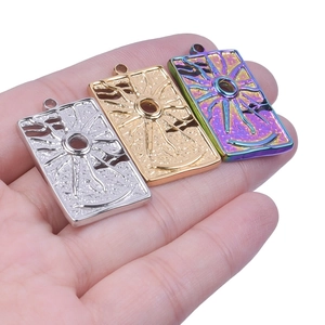 Macro view of sun eye rectangular pendants in gold, silver, and rainbow steel