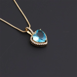 Detail of a gold heart pendant with a blue center stone and white diamond accents