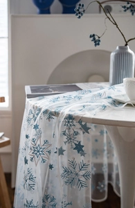Close-up of white tulle tablecloth featuring blue glitter snowflakes and stars patterns