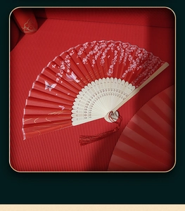 Detail of red folding fan with cherry blossom pattern, hollow bamboo ribs and tassel
