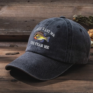 Close-up of vintage washed cotton baseball cap with fish embroidery and slogan on wood